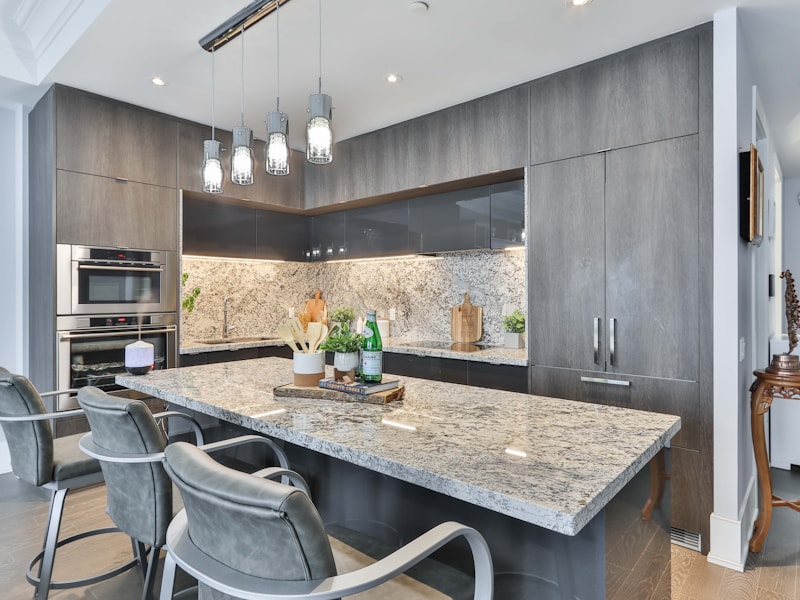 Cocina moderna con isla central, gabinetes grises y cubierta de granito